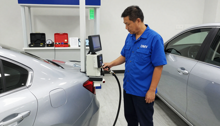 Technician using a handheld scanner on a white car for smog check service in Baldwin Park, CA