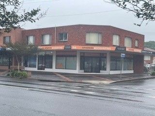 Corner brick storefront on a rainy street with orange awnings and large windows.