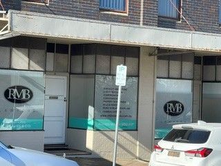 Street-level storefront with RMB signs, glass doors, and a white SUV parked in front.