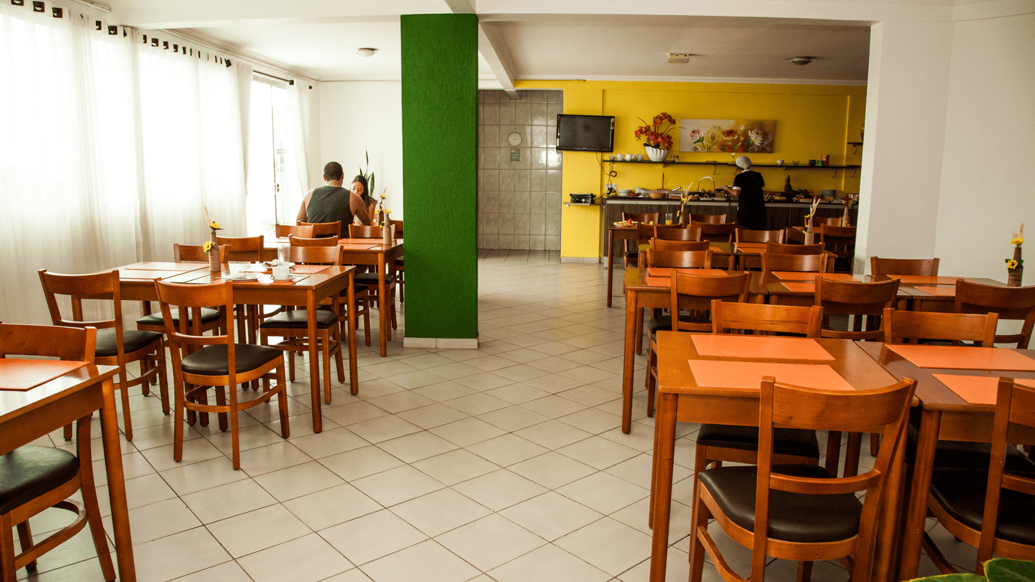 Um restaurante com mesas e cadeiras e uma parede verde