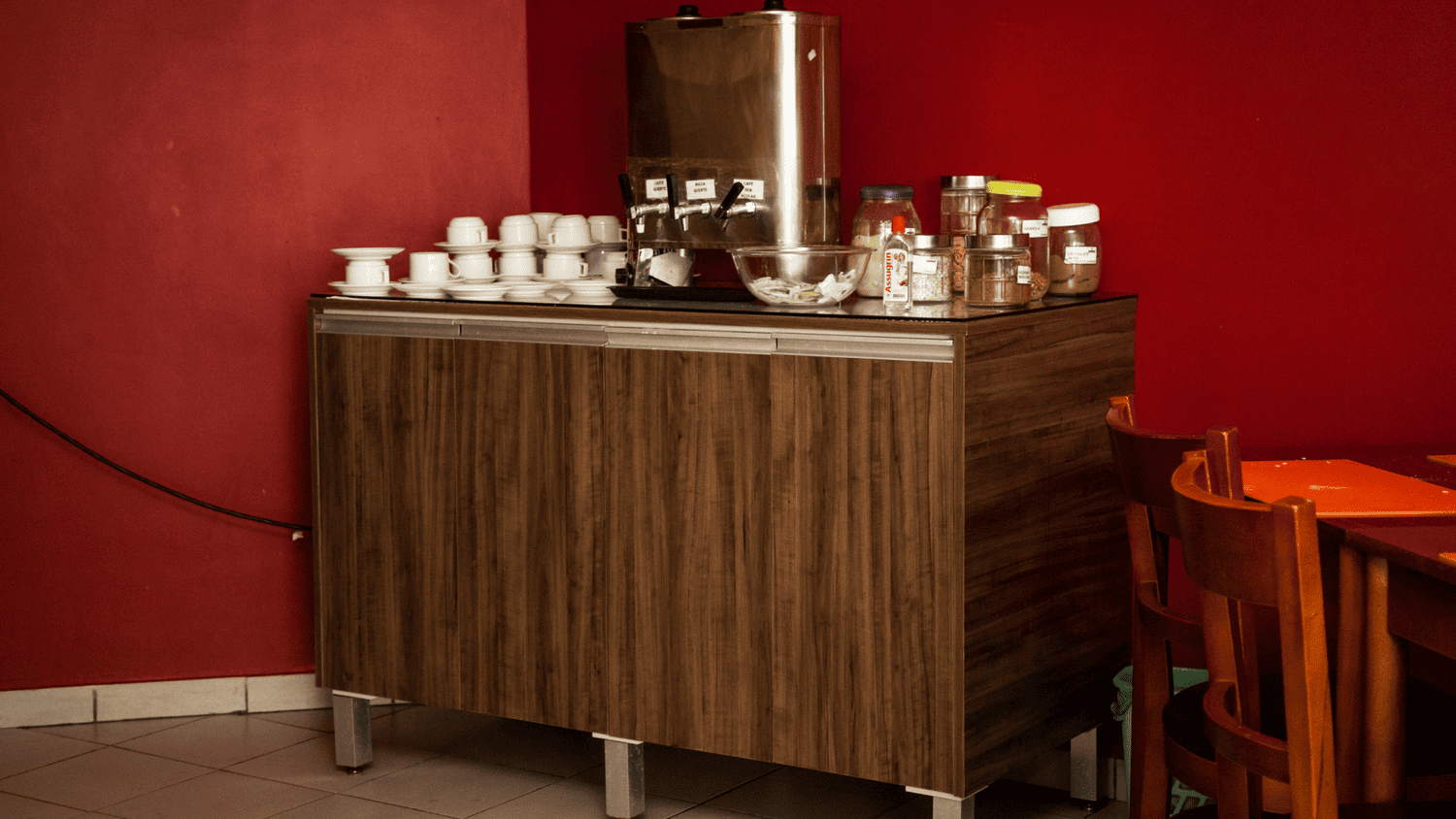 Uma mesa de madeira com uma cafeteira e xícaras em cima dela em um restaurante.