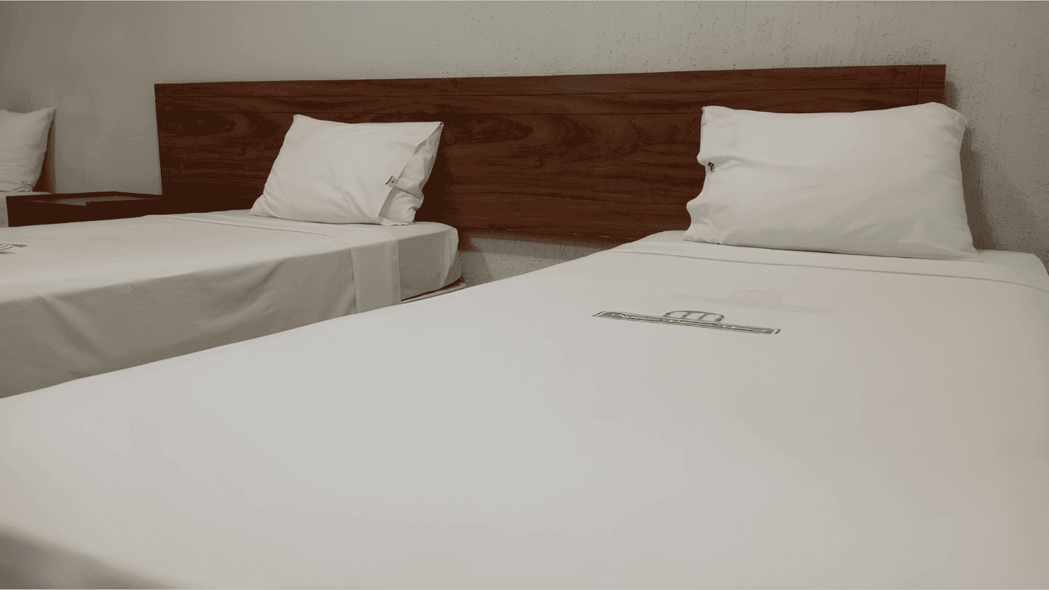 Um quarto de hotel com duas camas e uma cabeceira de madeira.