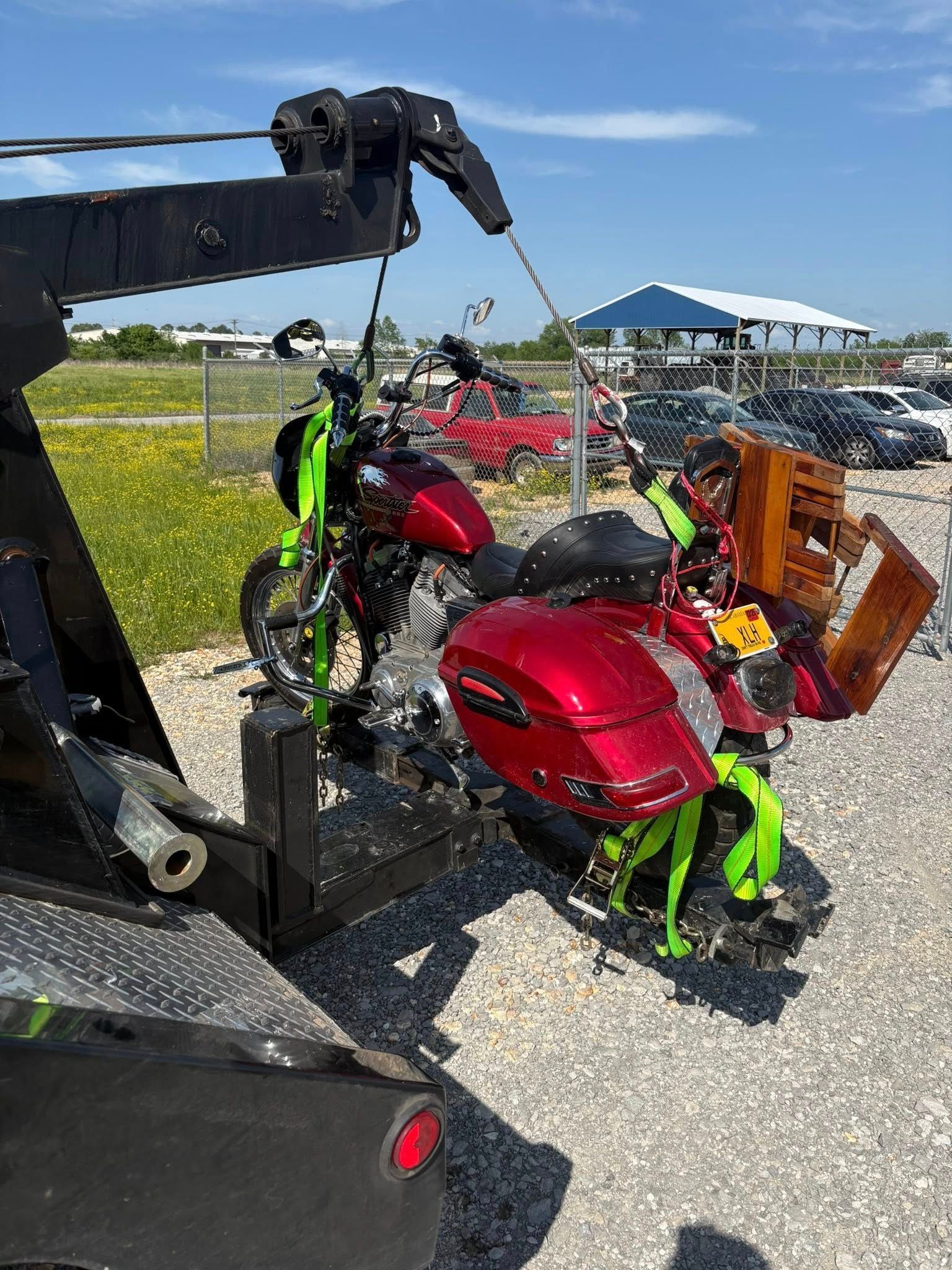 Two red and green motorcycles strapped on a tow truck at an outdoor lot