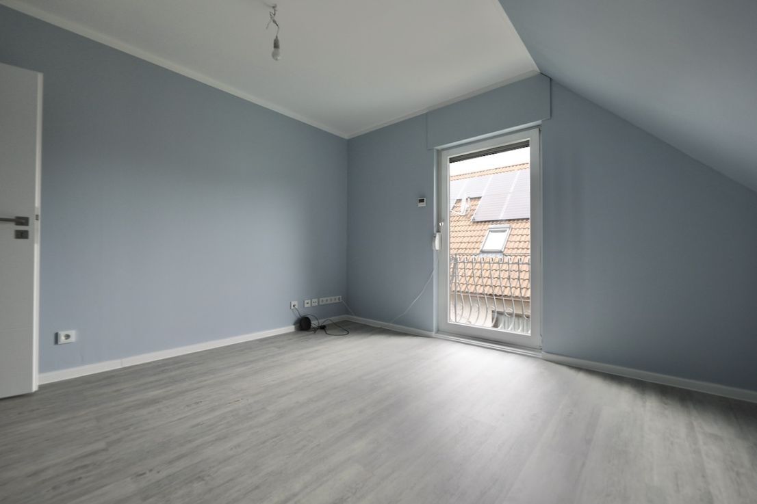 An empty room with a sliding glass door and a balcony.