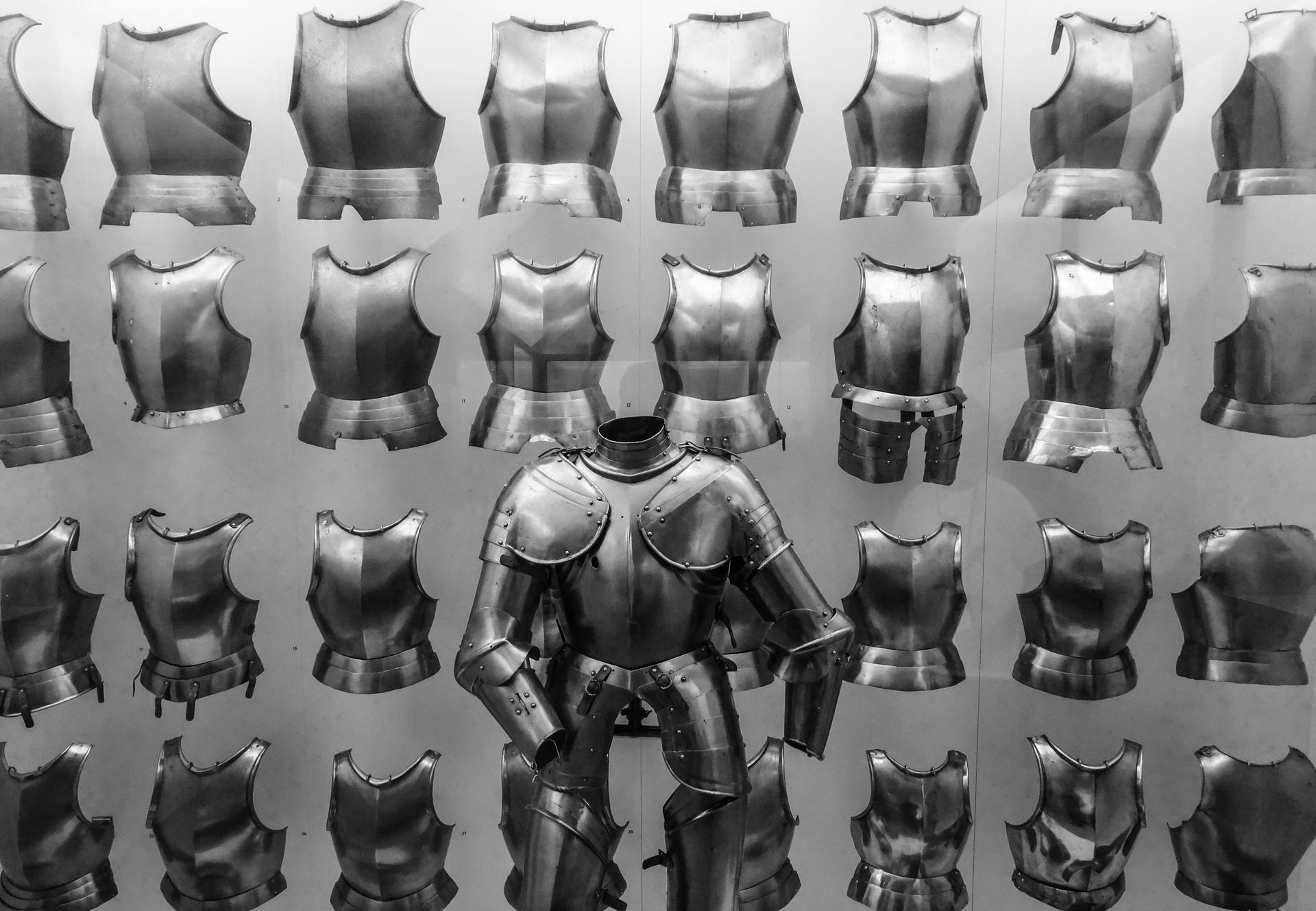 Display of medieval metal armor breastplates and a full suit of armor in a museum setting.