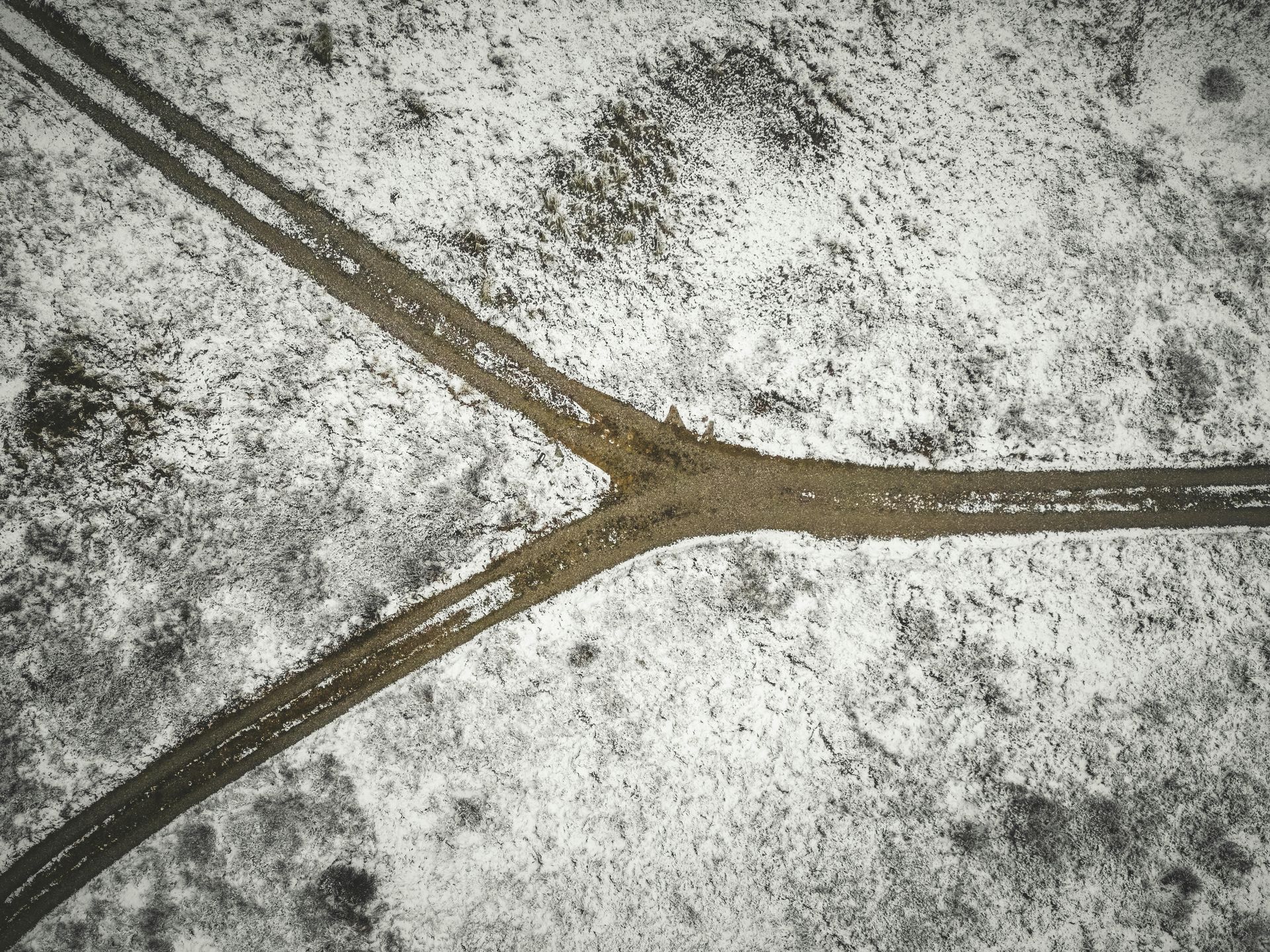 Forking dirt road in a snow-covered landscape.