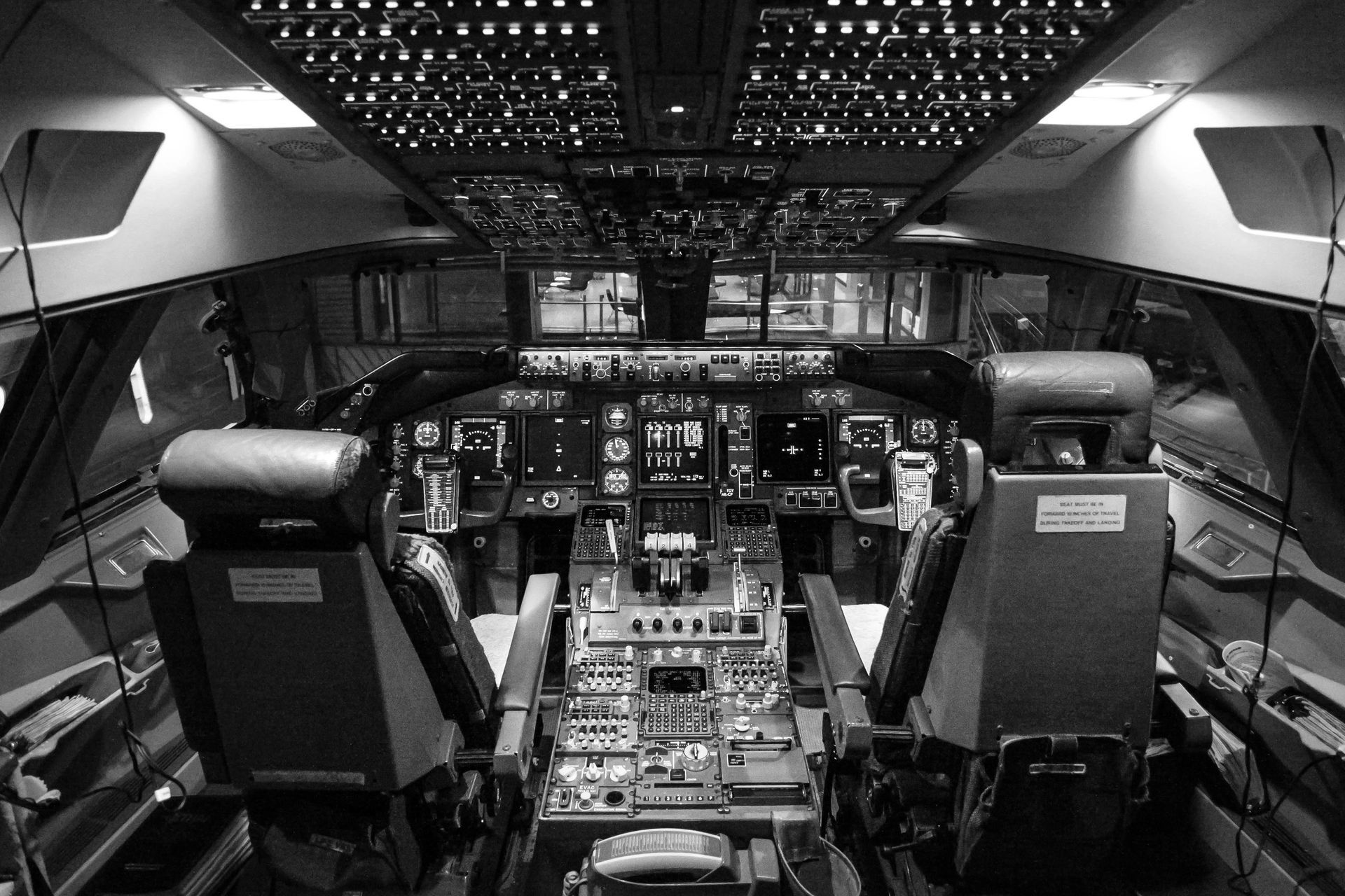 Cockpit interior of an airplane with instrument panels, pilot seats, and overhead lighting.