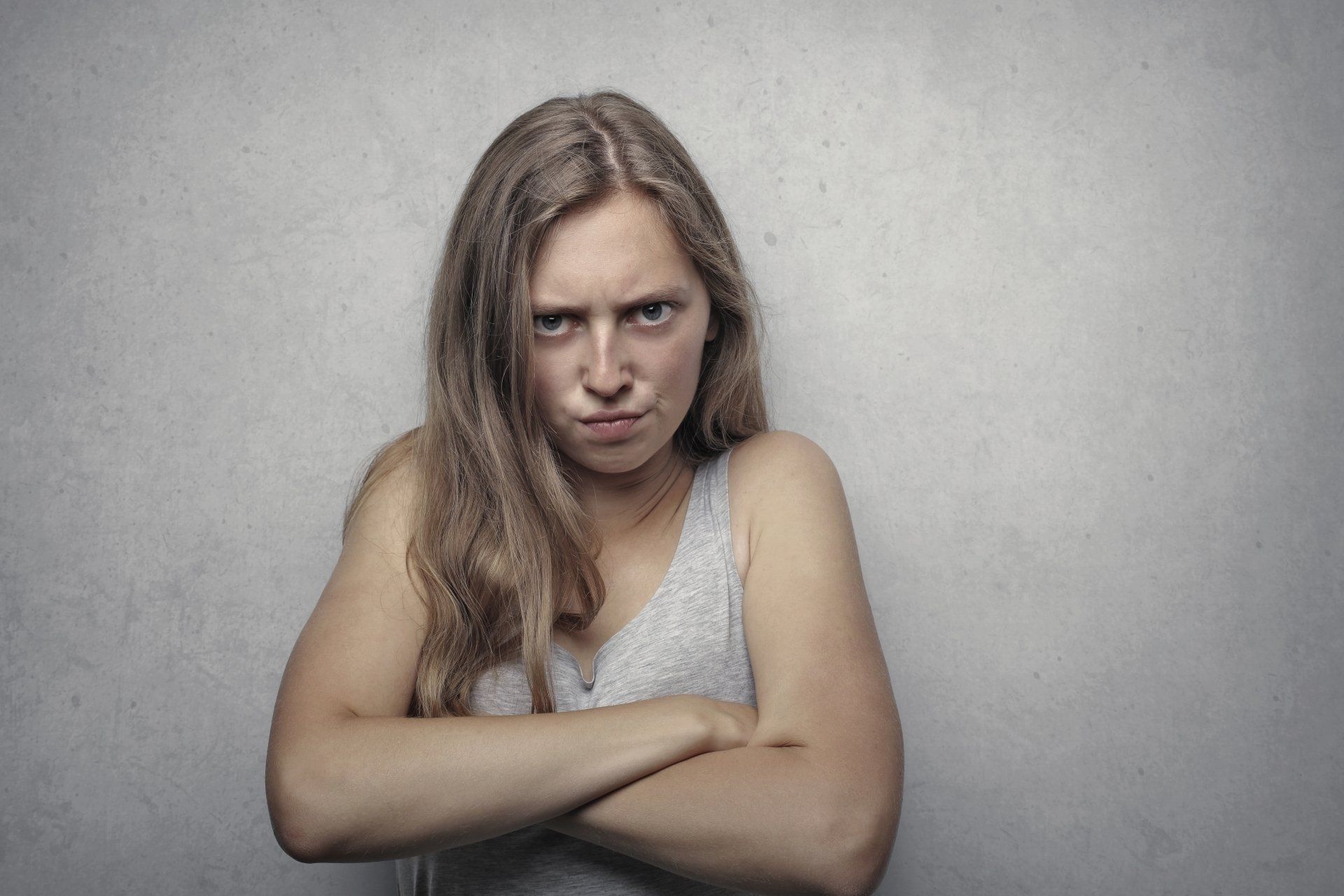 Woman with arms crossed, frowning, looking directly at the viewer with an angry expression