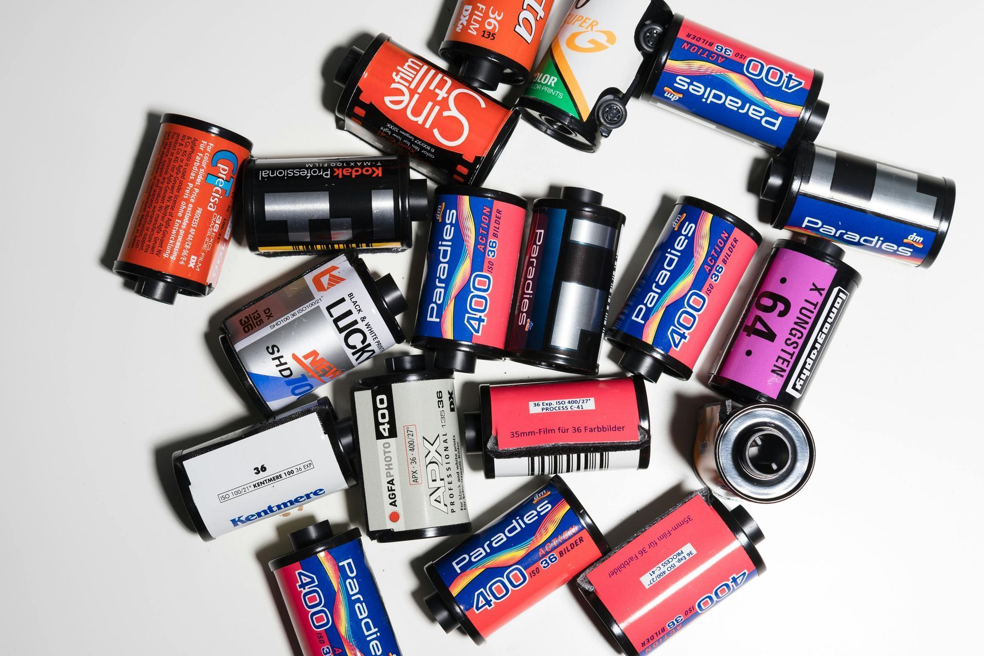 Pile of various colorful 35mm film canisters on a white surface, some with visible branding and labels.