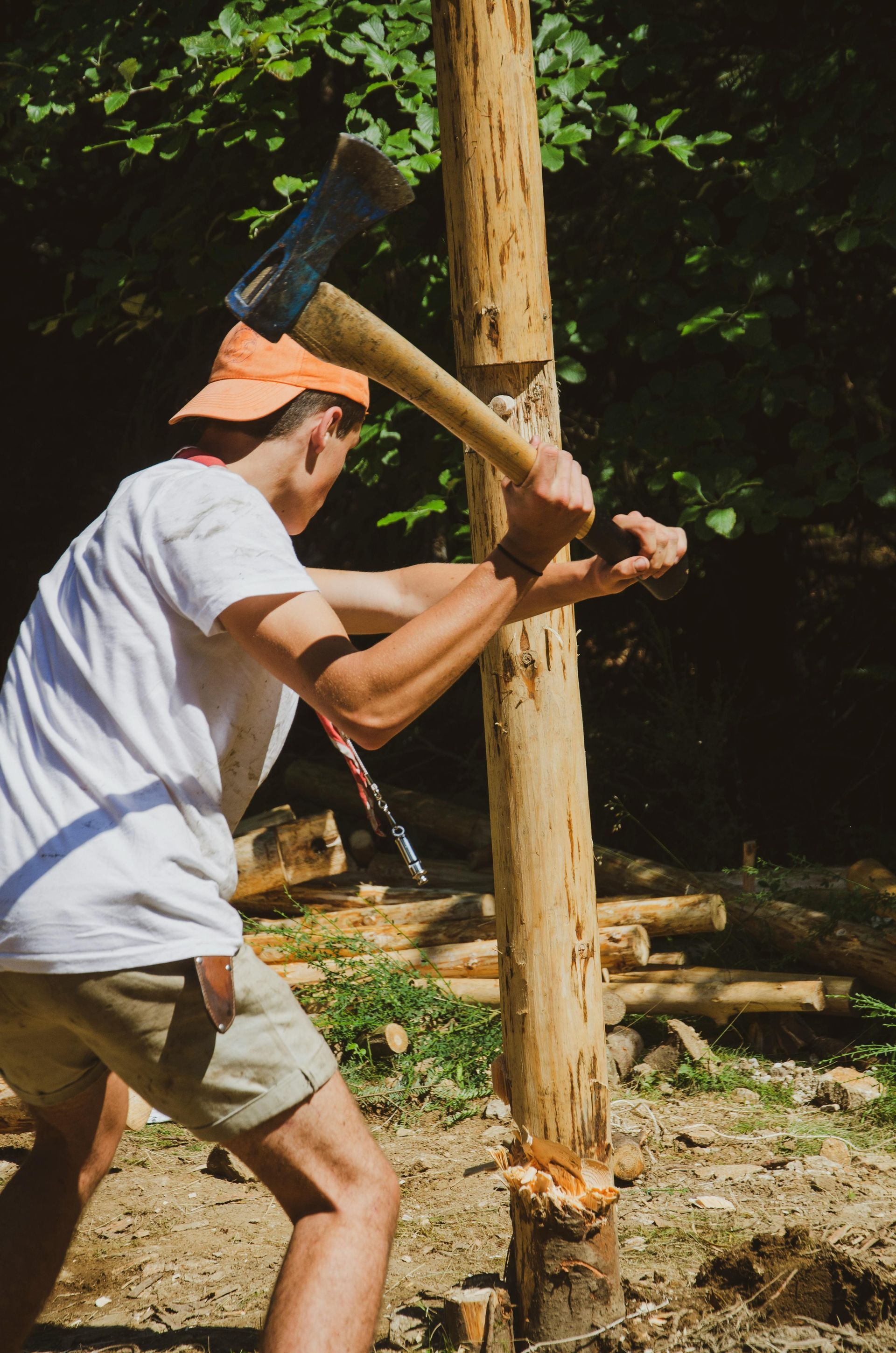 Person chopping a wooden post with an axe outdoors.