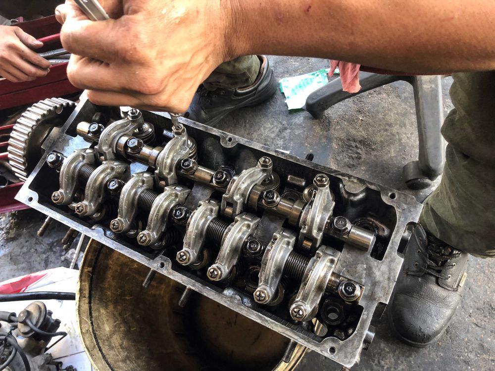 Hands Adjusting a Car Engine’s Exposed Valve Train With Rocker Arms and Camshaft — M T Automotive In Wallsend, NSW