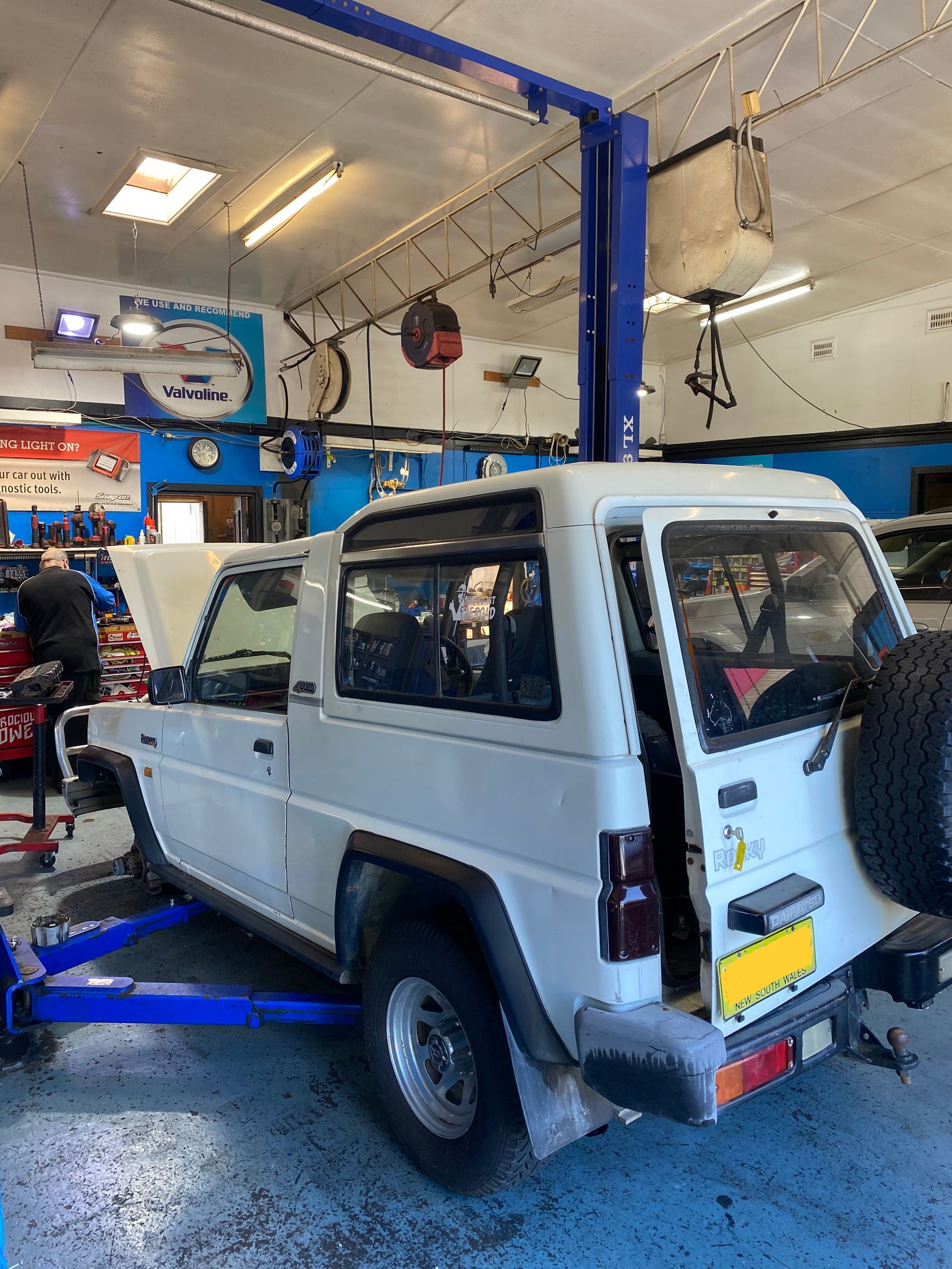 White SUV on a Lift Inside an Auto Repair Shop — M T Automotive In Wallsend, NSW