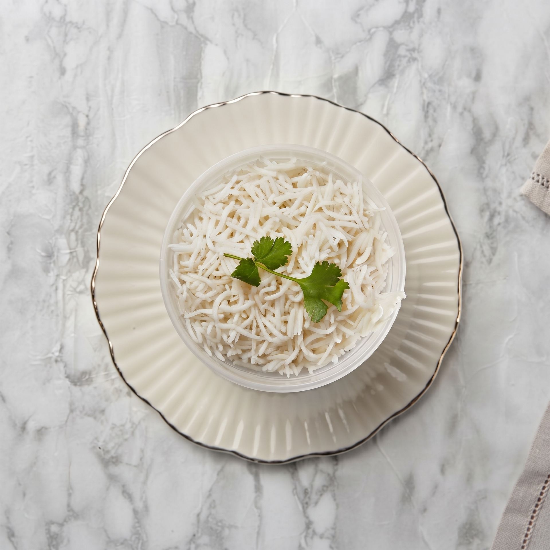 White shredded dessert in a bowl on a fluted plate, garnished with mint, on a marble table
