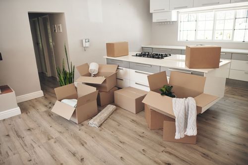 A kitchen with a lot of cardboard boxes on the floor.