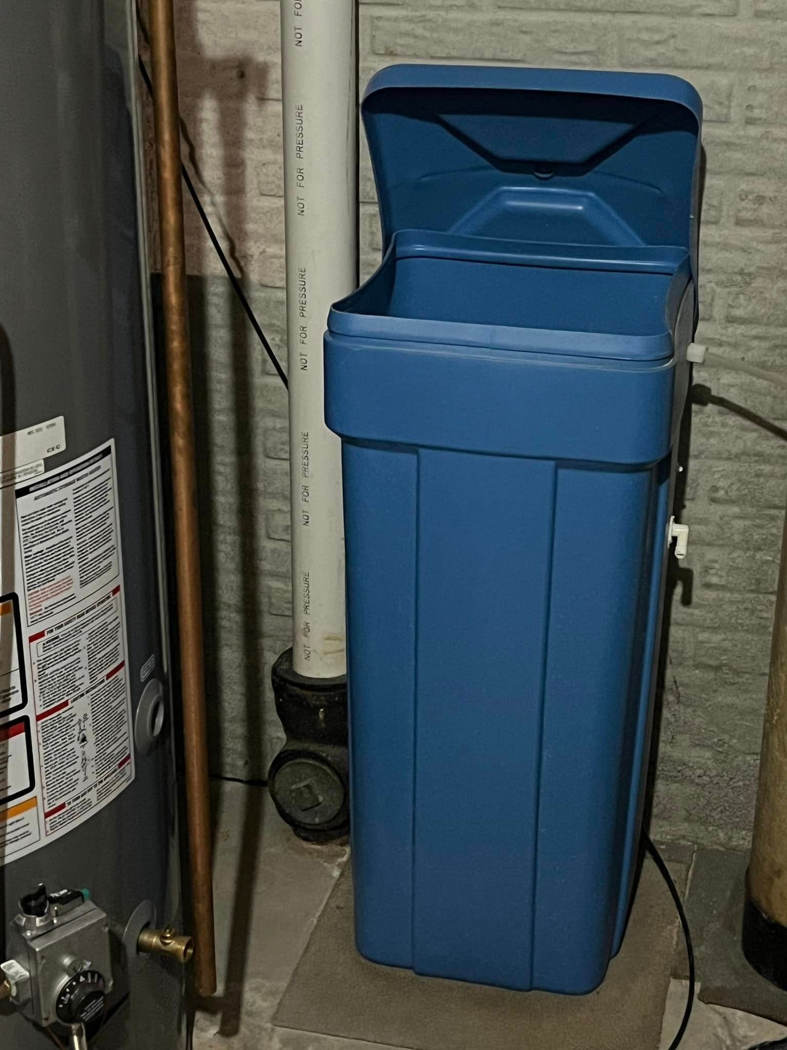 A blue trash can is sitting next to a water heater