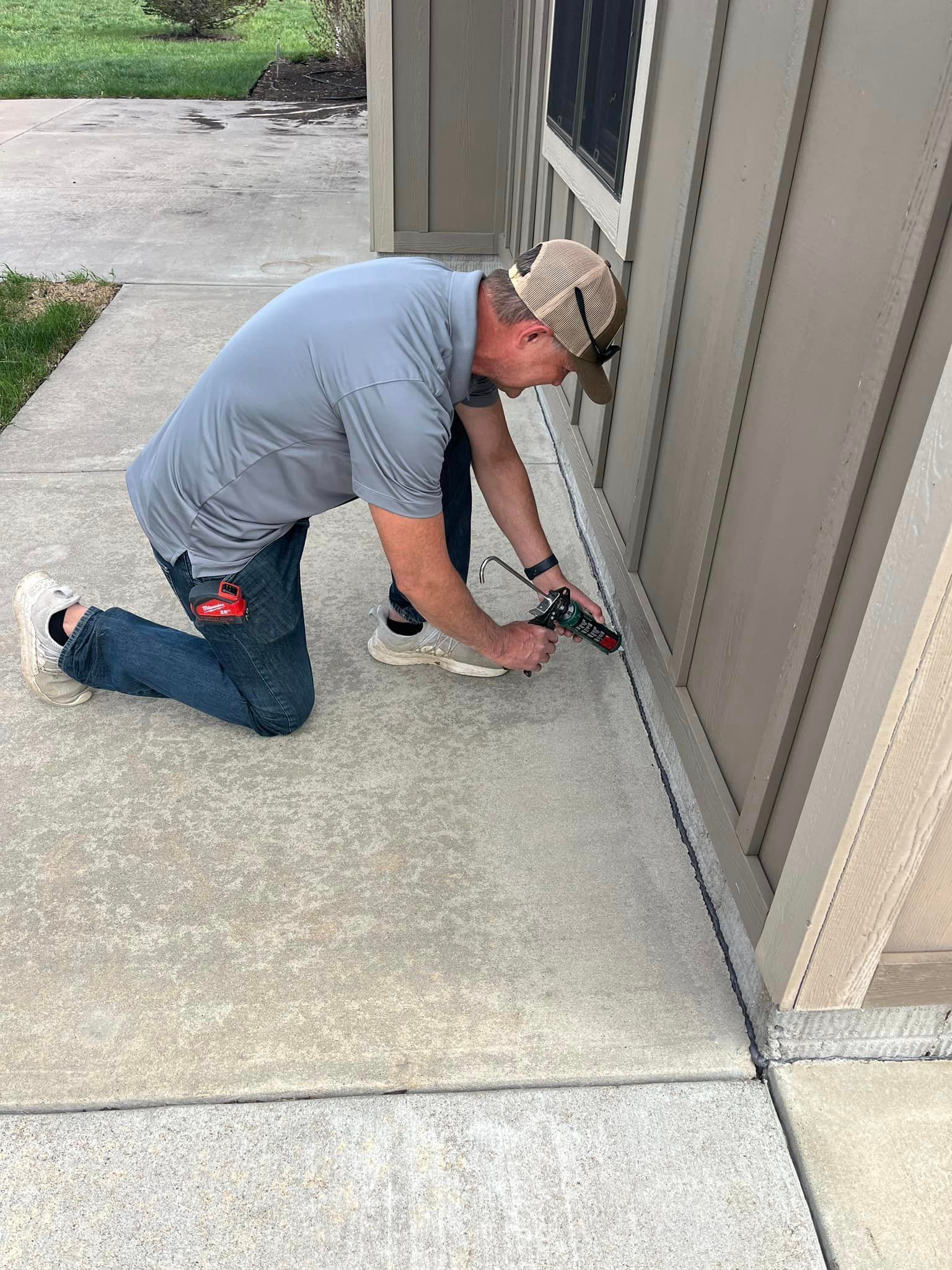 A man is kneeling down on the sidewalk next to a building.
