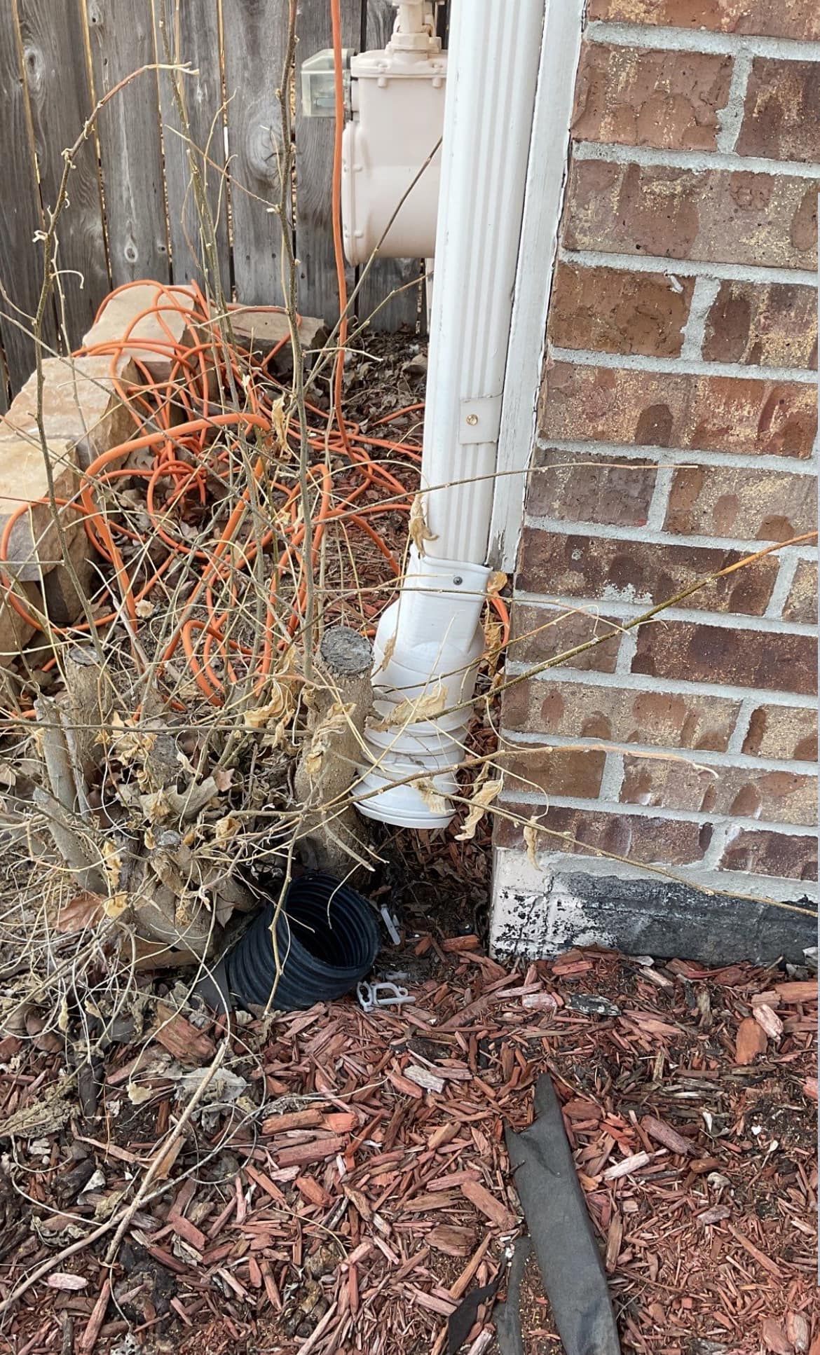 A drainpipe is sitting on the side of a brick building.