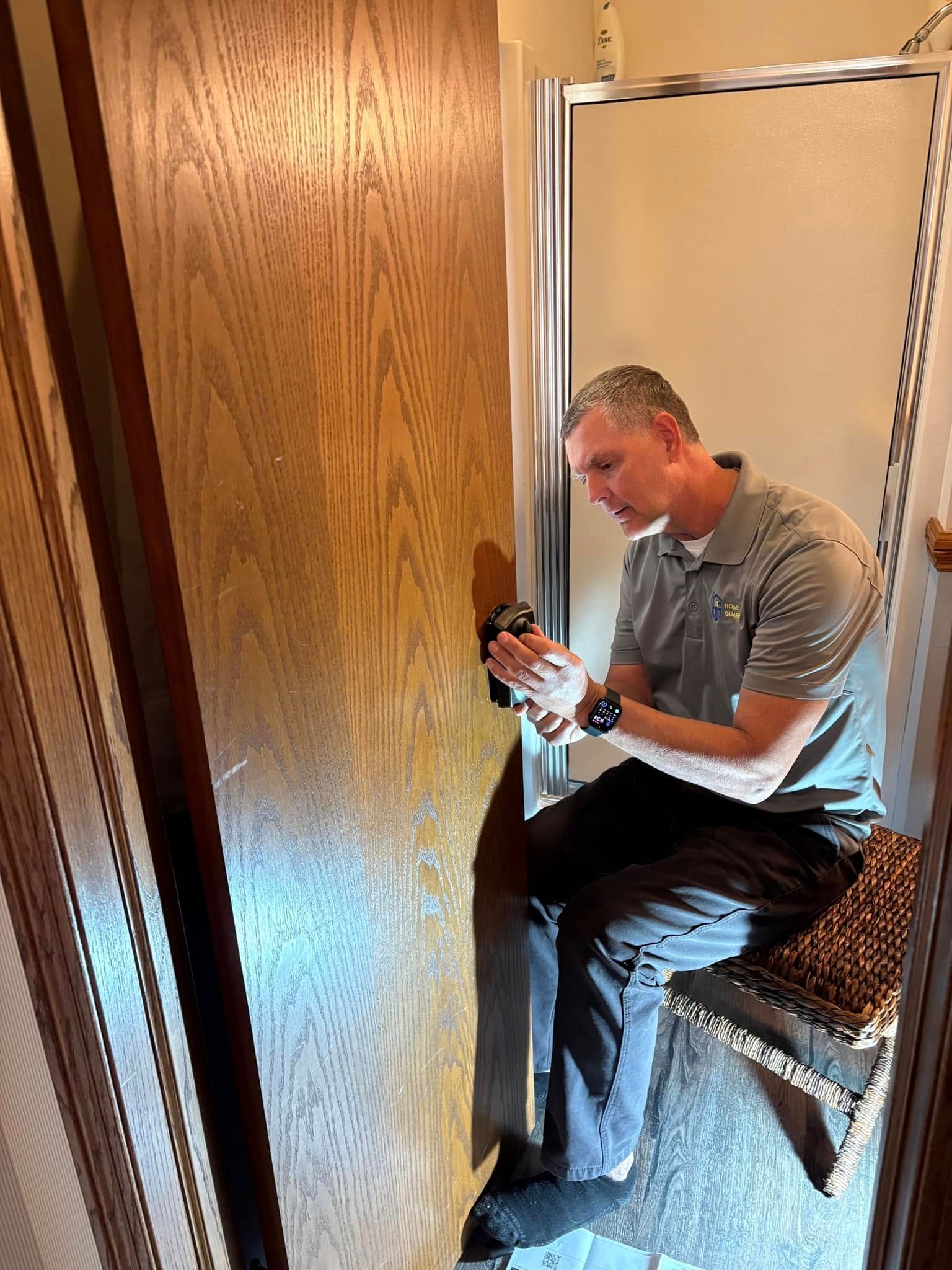 A man is sitting in a bathroom looking at a door.