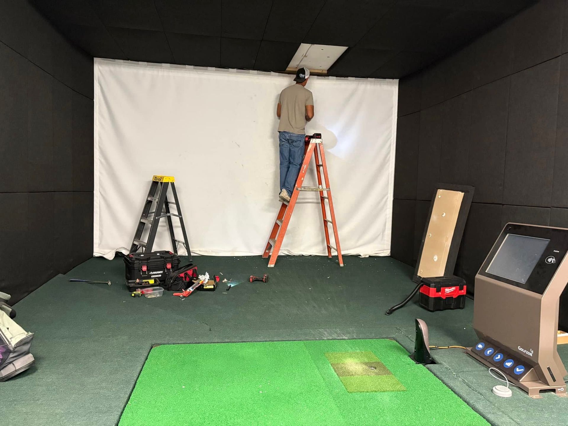 A man is standing on a ladder in a room.