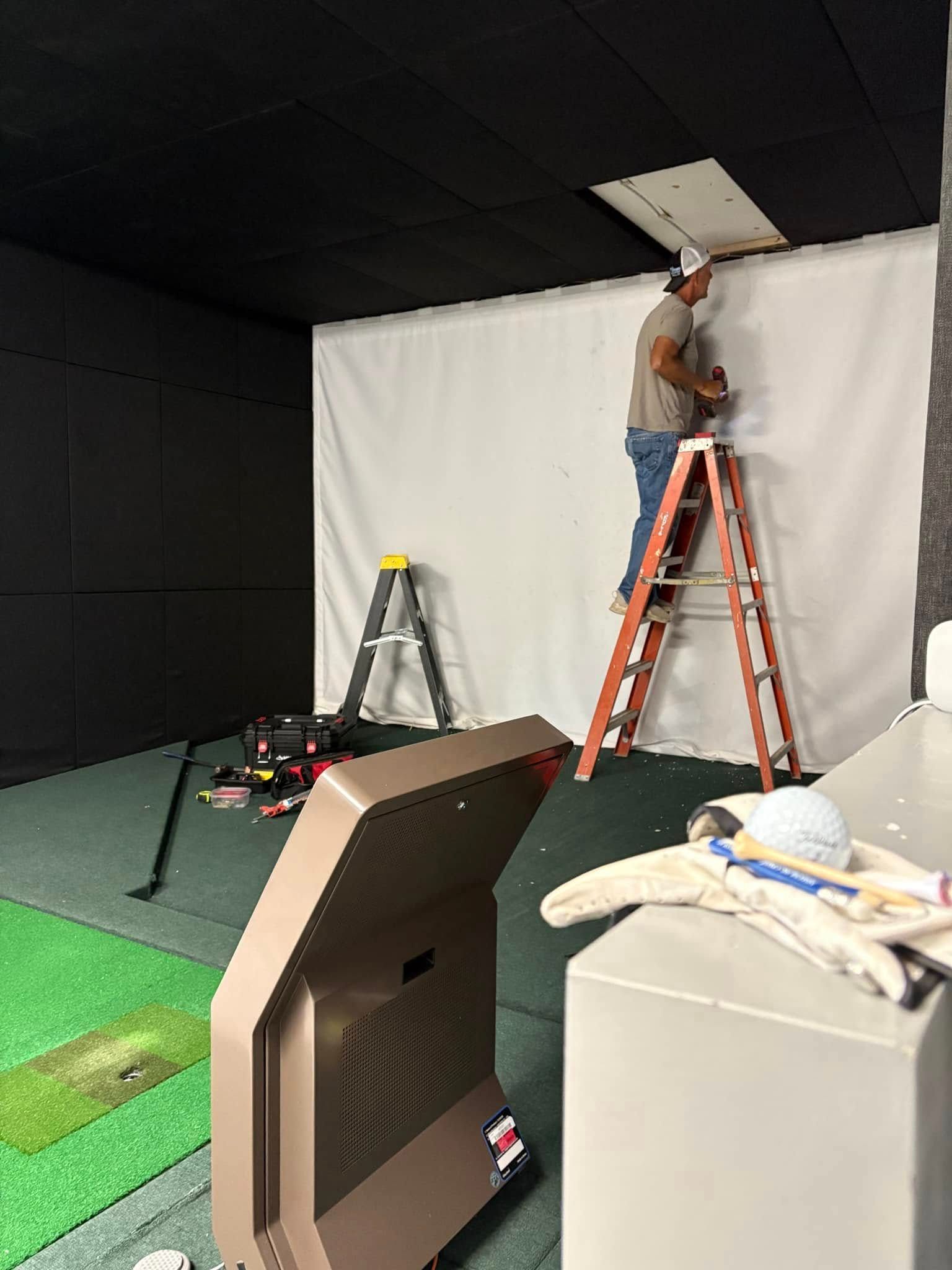 A man is standing on a ladder in a room.