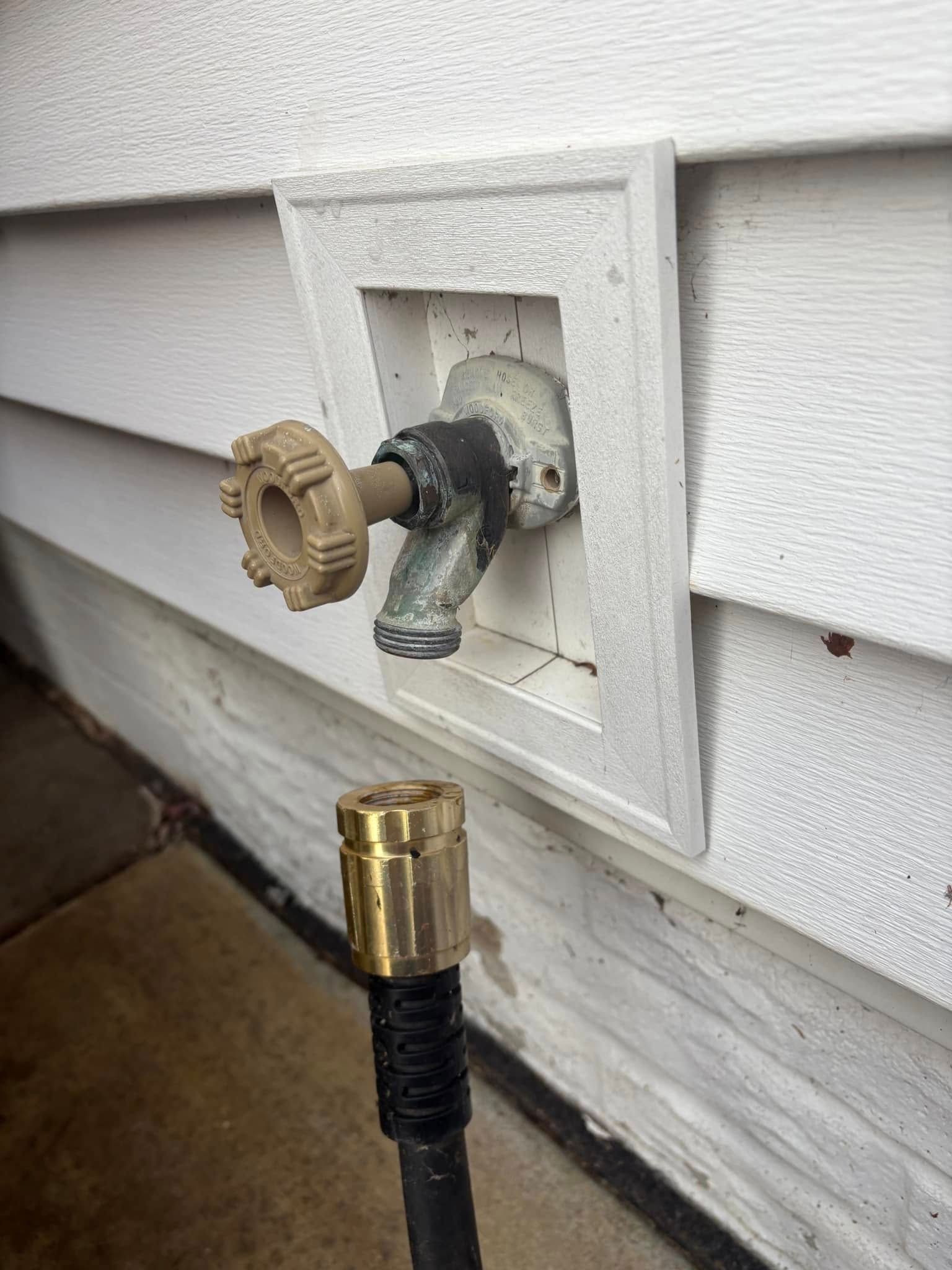 A hose is connected to a faucet on the side of a house.