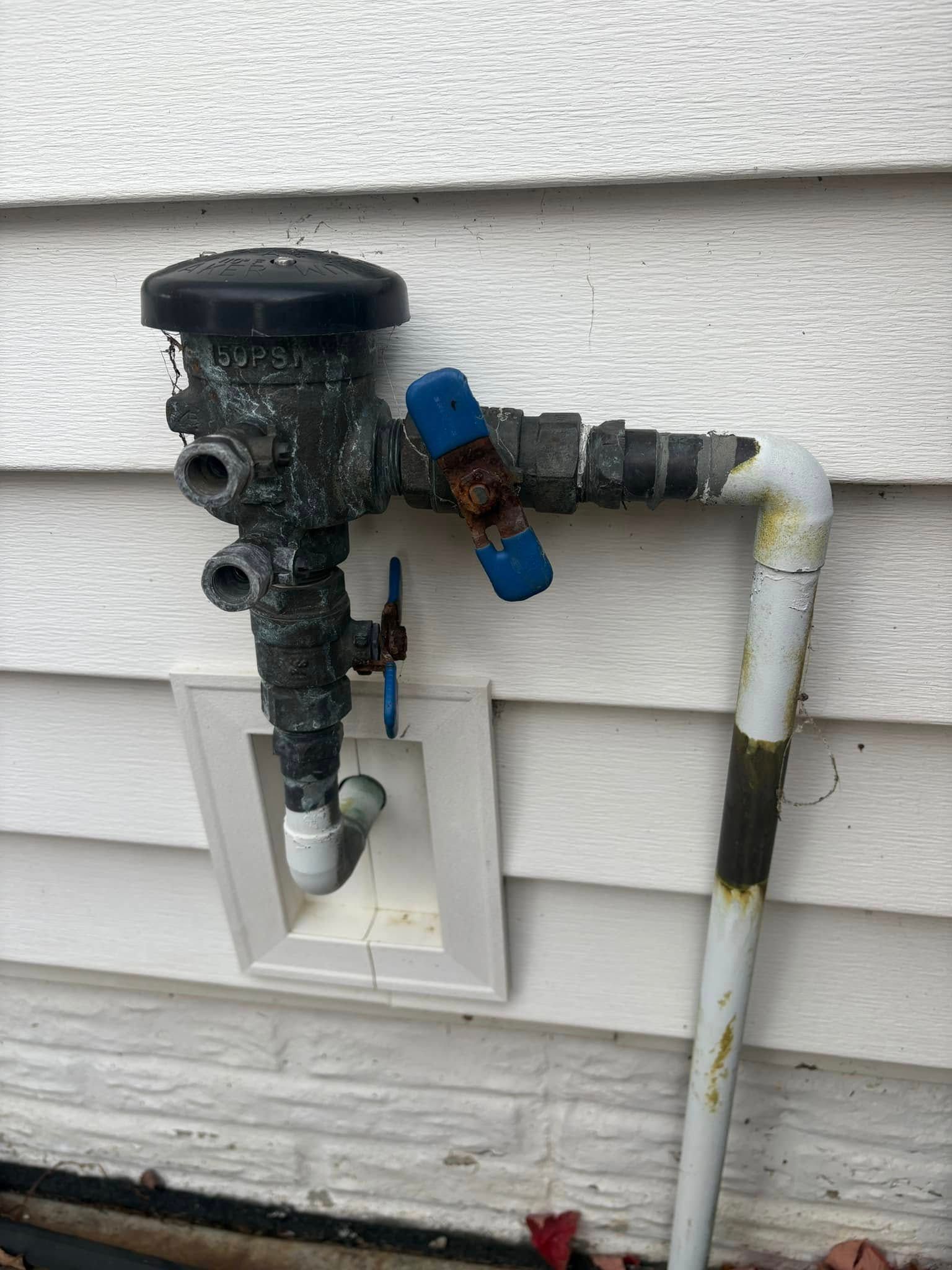 A close up of a water pipe on the side of a house.