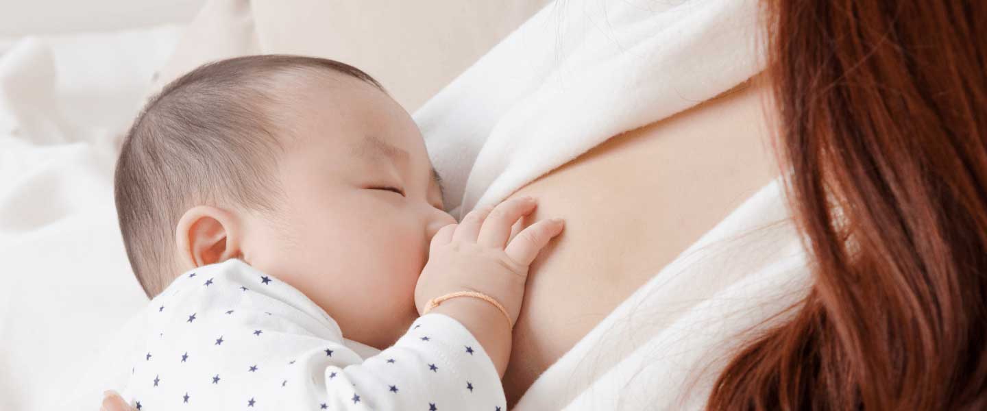 Sleeping baby breastfeeding on a mother's chest