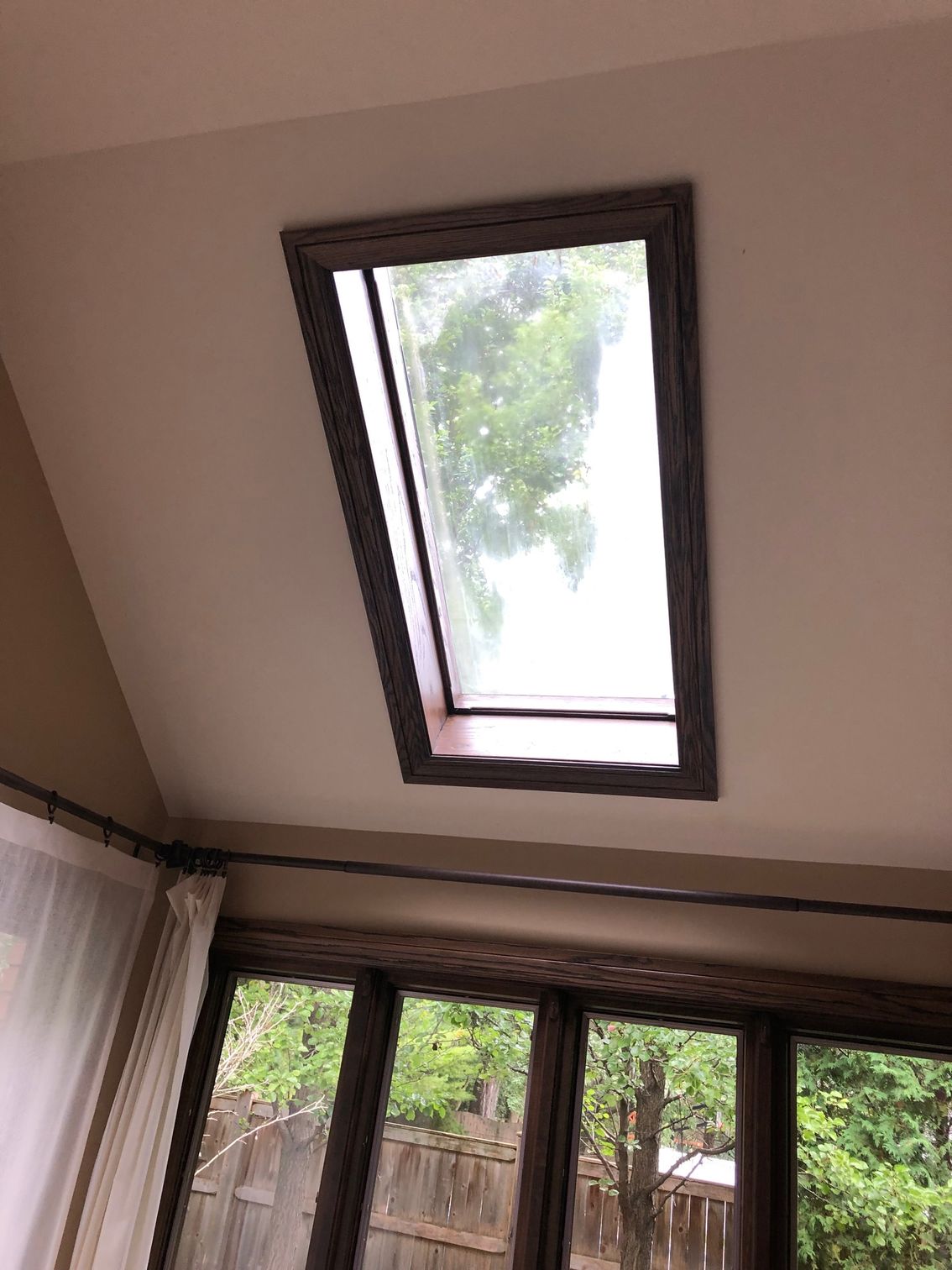 There is a skylight in the ceiling of a room with a lot of windows.