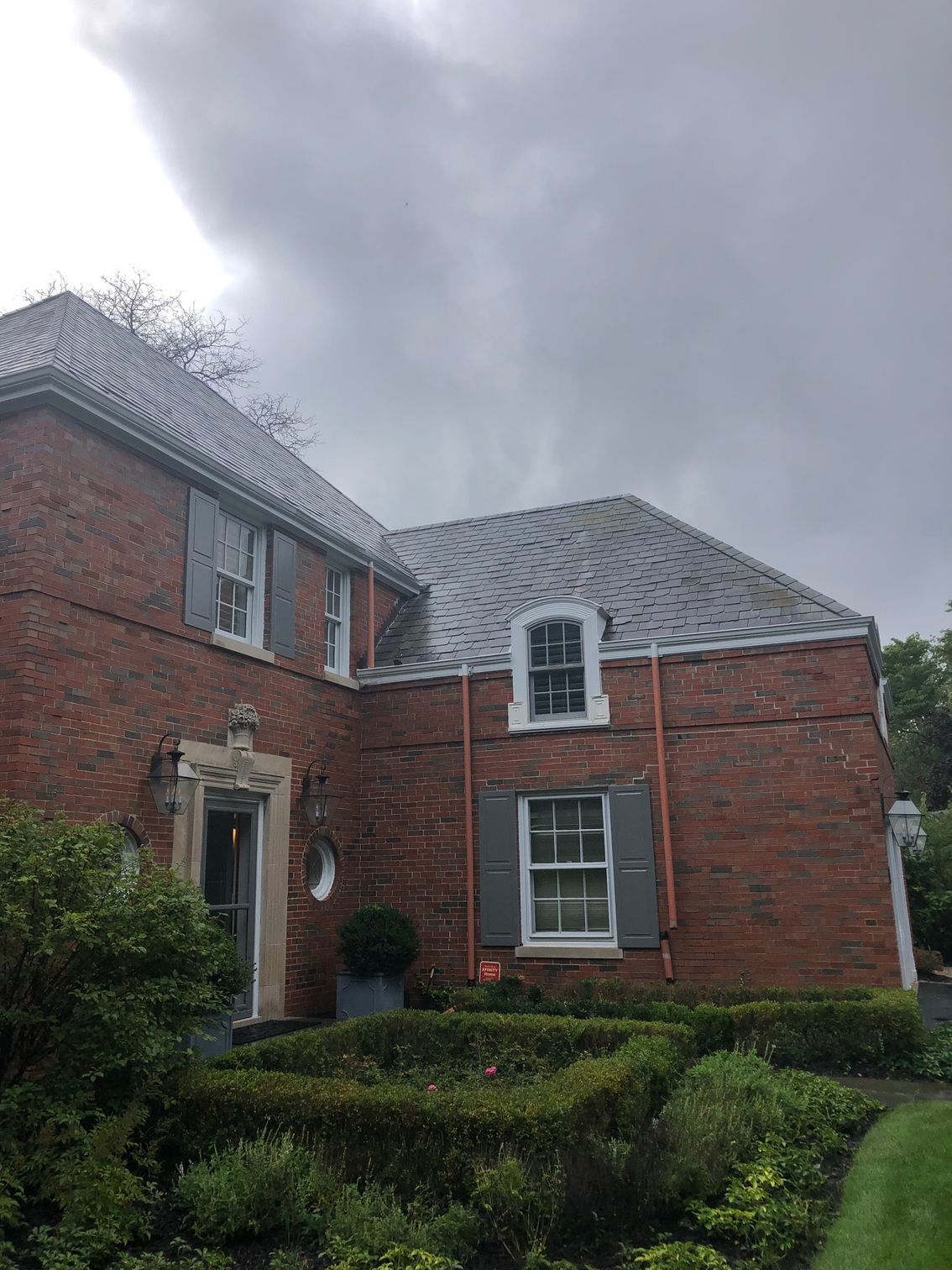 A large brick house with a gray roof and white shutters.