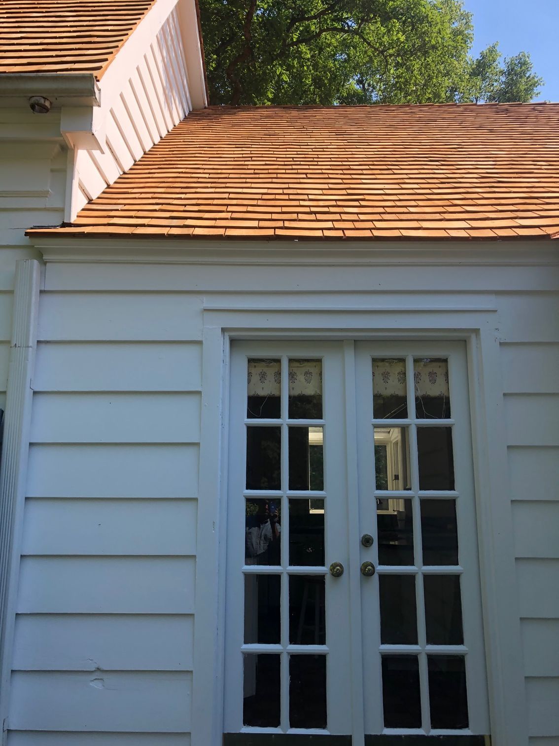 A white house with a wooden roof and french doors