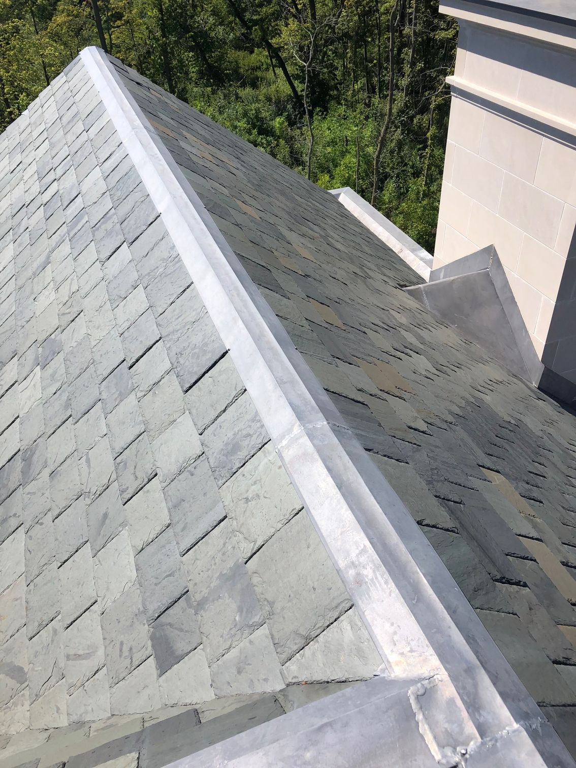 A close up of a roof with shingles and a metal gutter.