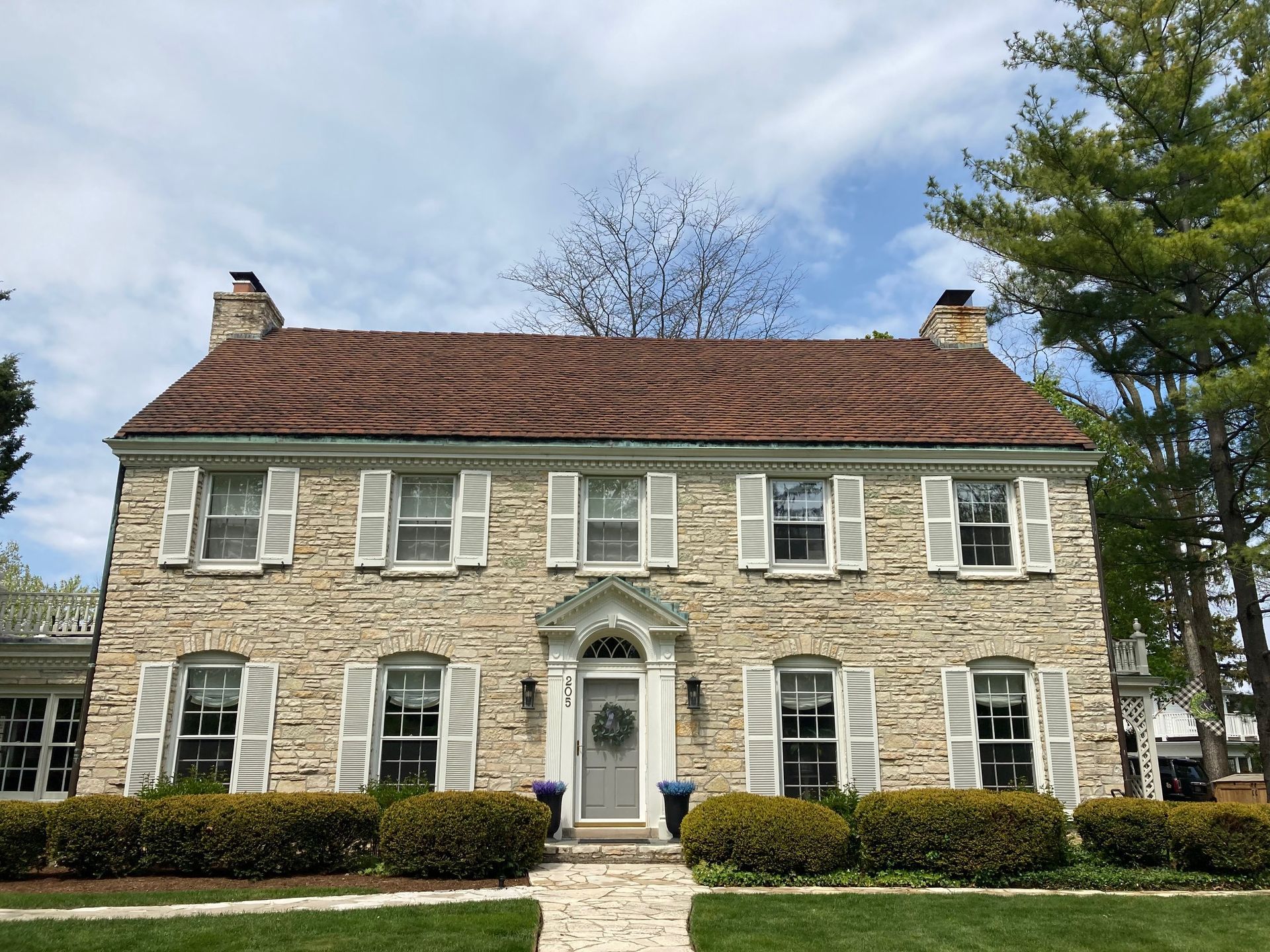 A large stone house with white shutters and a brown roof.