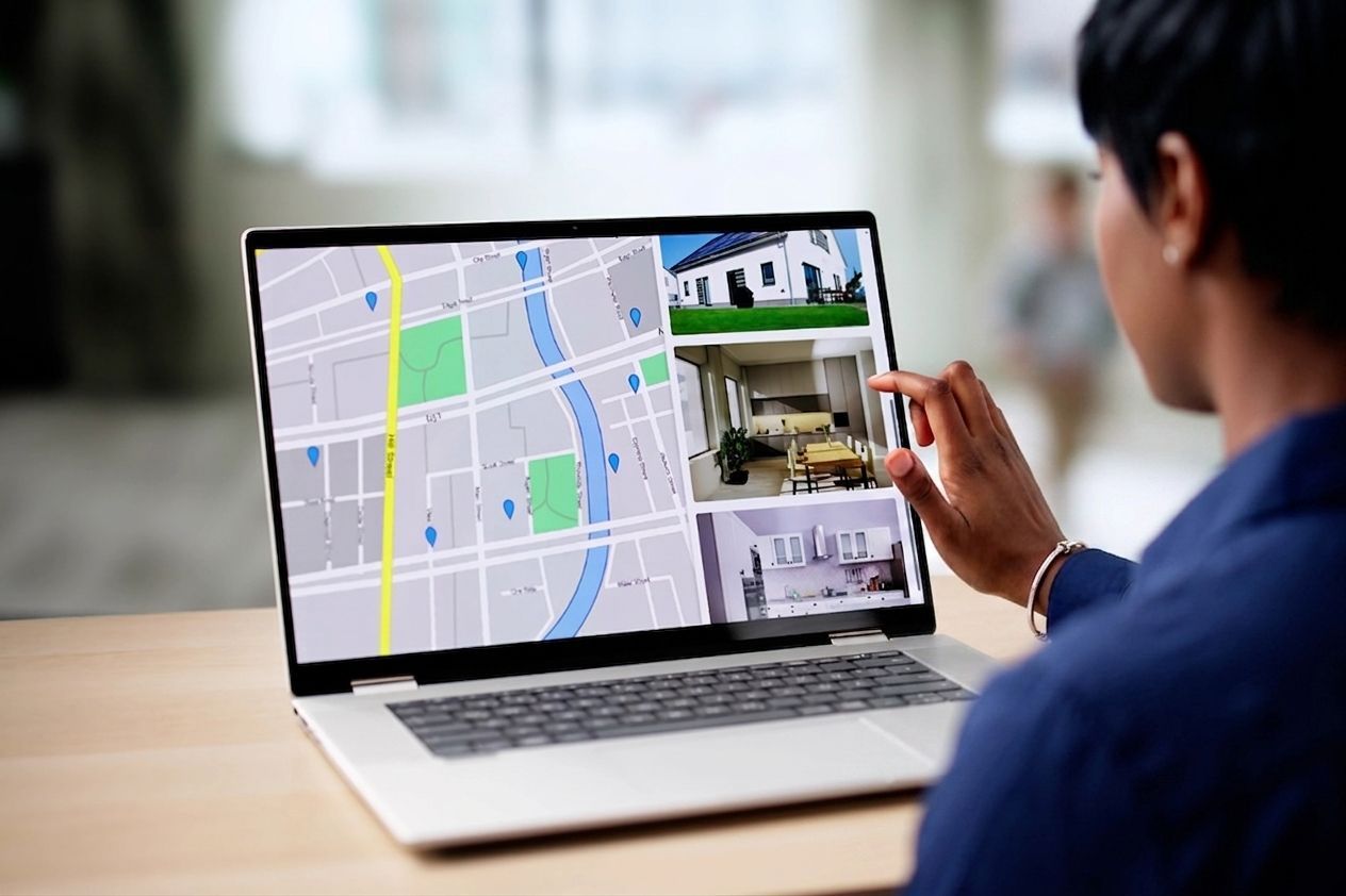 Person reviewing a laptop screen with a map and property photos in a home search setting