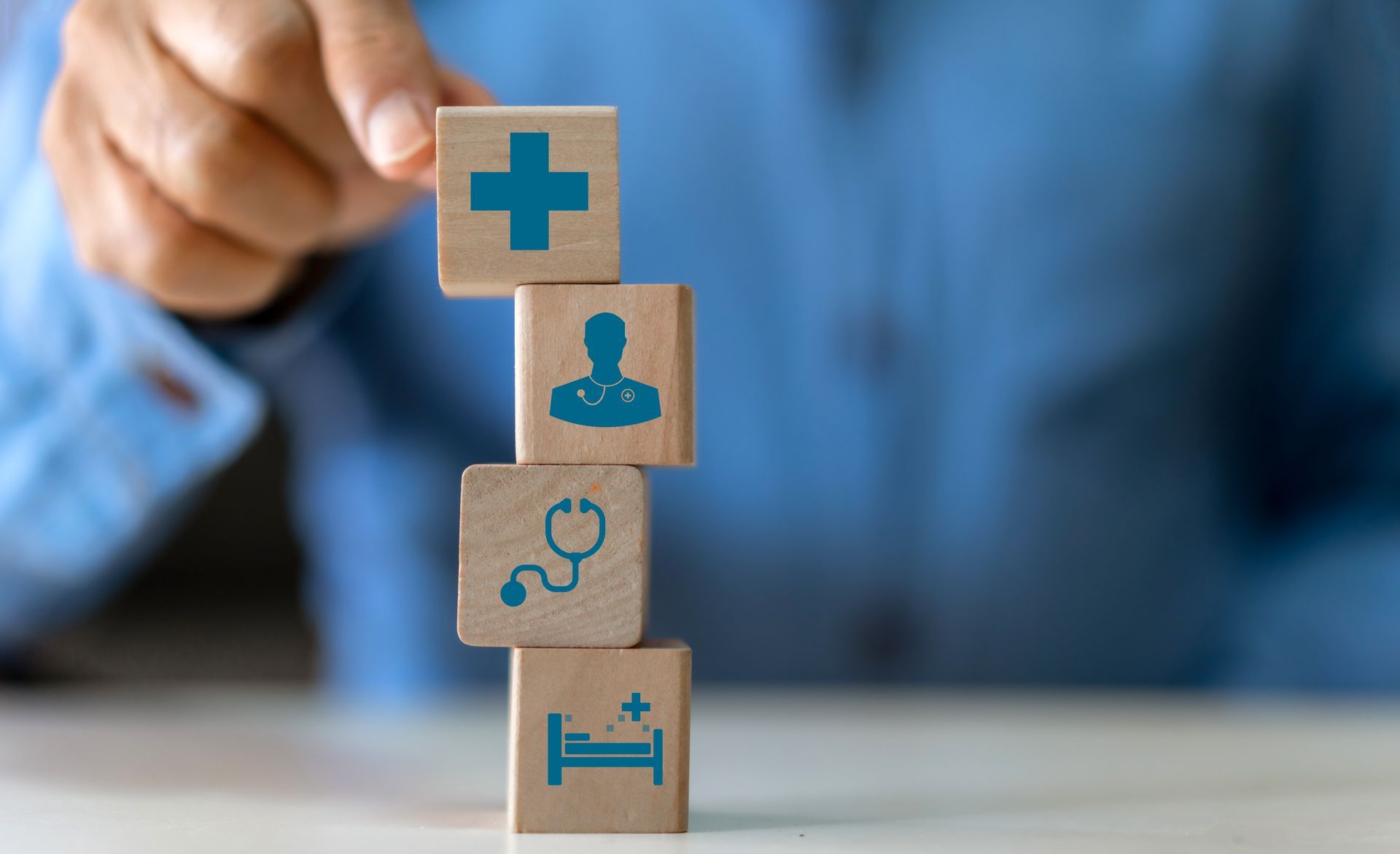 Stacked medical blocks with health icons and a hand placing the top block on a table