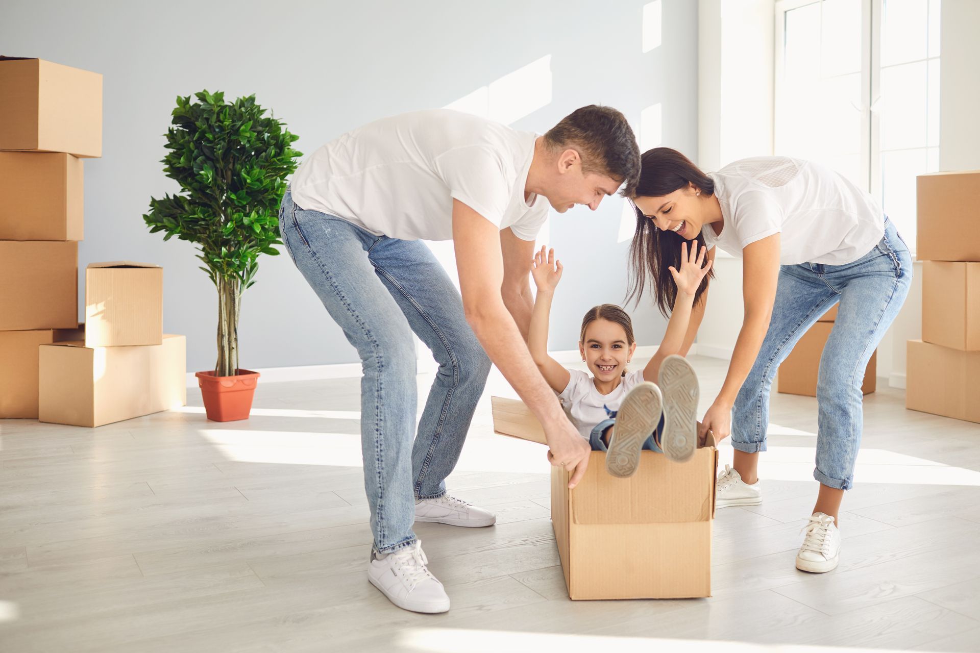 Family packing a baby into a cardboard box in a bright moving room