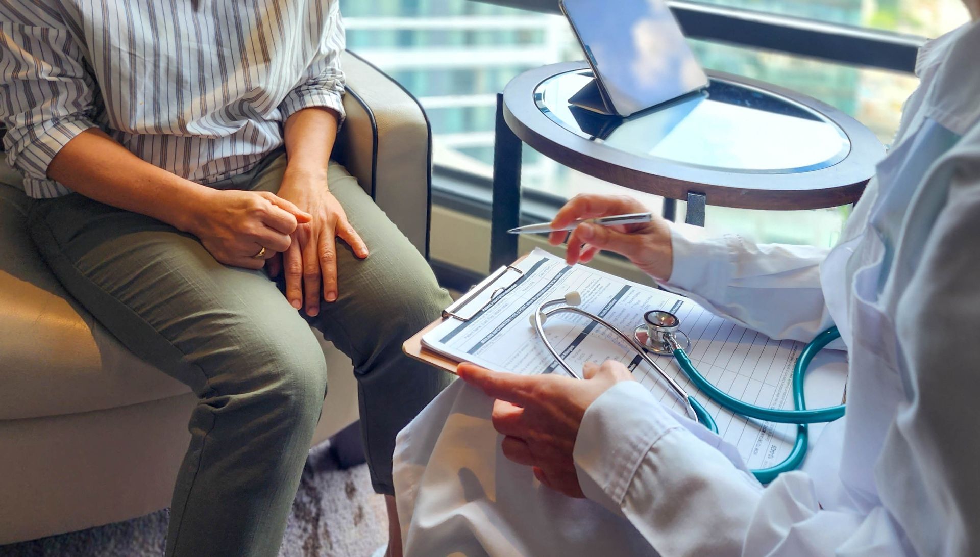 Doctor reviewing notes with seated patient in a clinic office