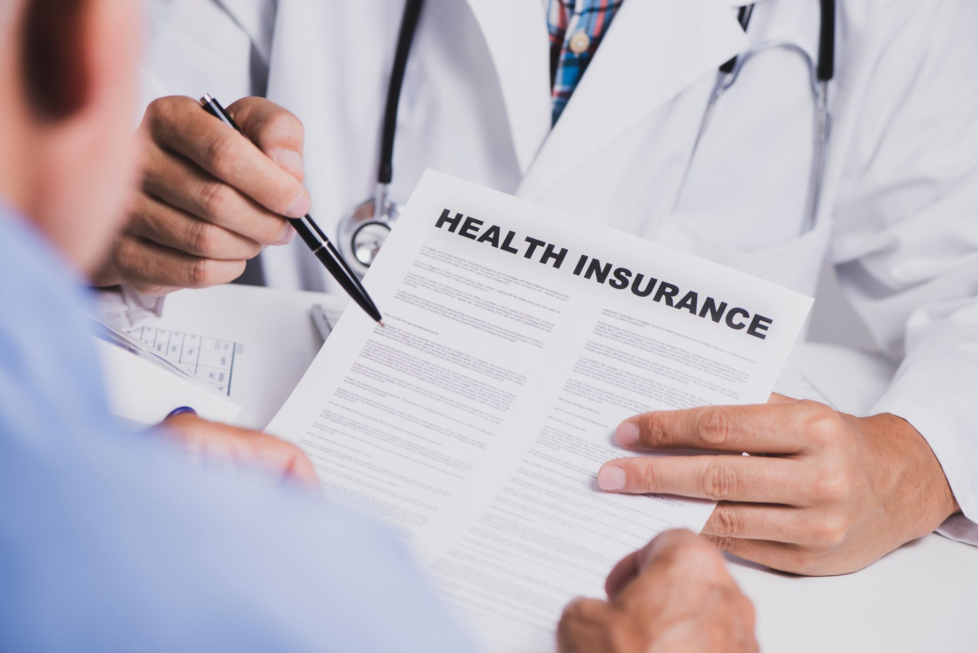 Doctor reviewing health insurance paperwork with a patient in a clinic