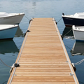 Wooden dock extending into calm blue water, with two white boats moored on either side.