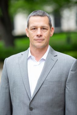 A man in a blue suit and white shirt is smiling for the camera.