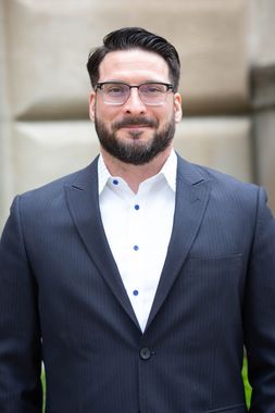 A man in a suit and white shirt is smiling for the camera.