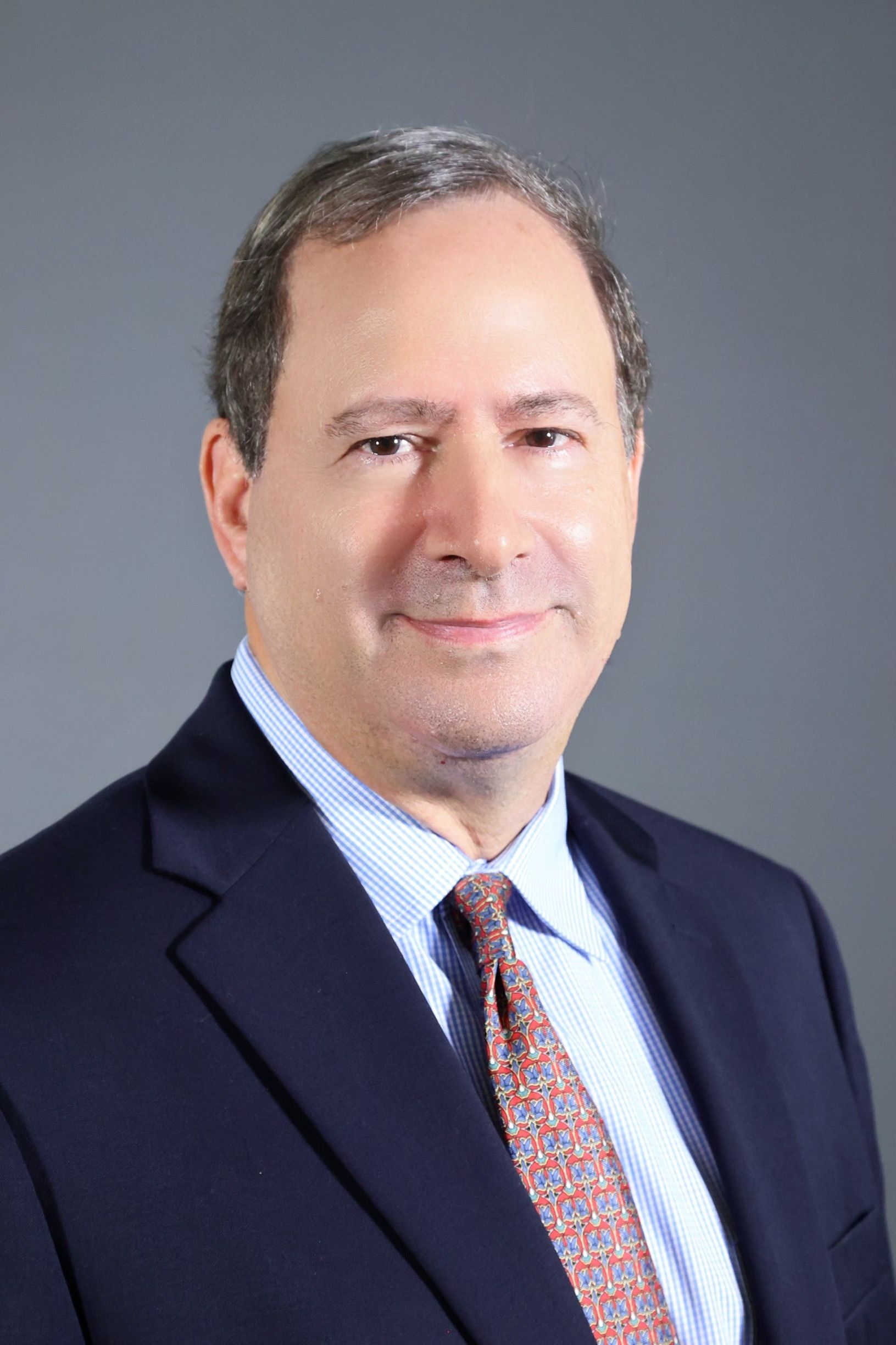 A man in a blue shirt and black pants is standing with his hands in his pockets.