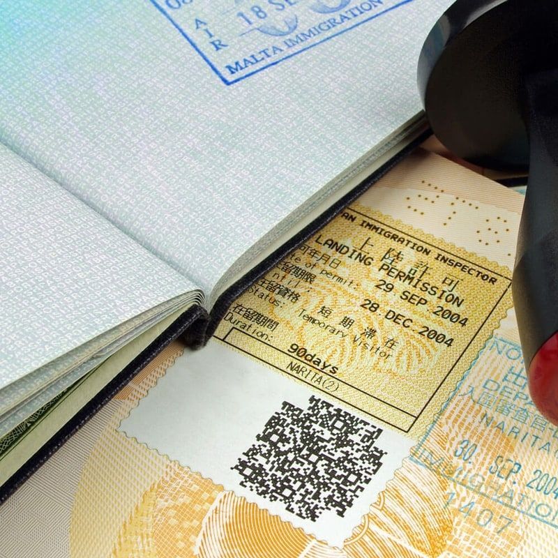 Passport pages open over a visa stamp and QR code in a close-up travel document scene