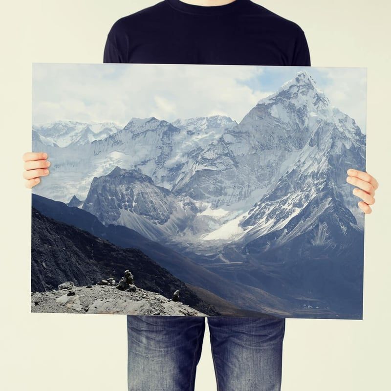 Person holding a large photo of snowy mountains and a glacier
