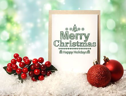 Merry Christmas card with red berries, ornaments, and snowy white backdrop