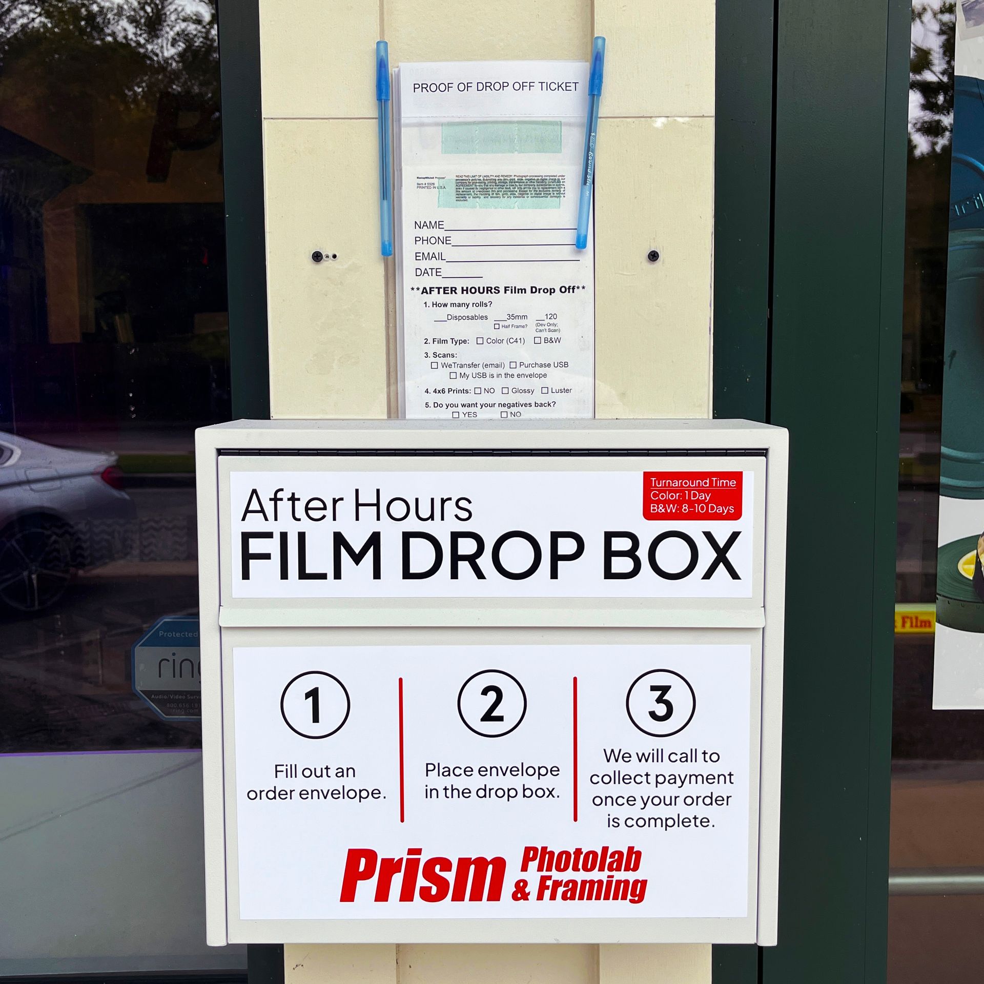 After-hours film drop box with step-by-step instructions outside a store window