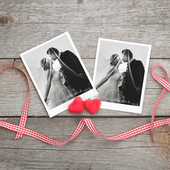 Black-and-white wedding photos with red hearts and ribbon on a wooden background