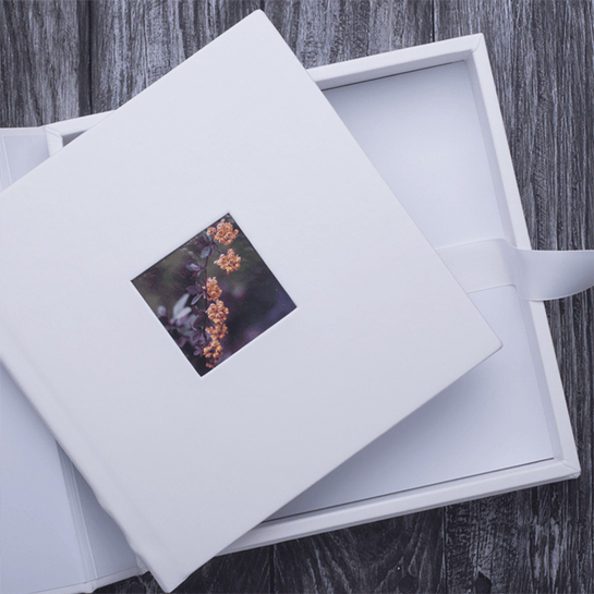 White photo album box with a floral cover photo on a gray wood surface