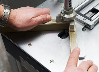 Hands measuring a metal machine part with a ruler on a workbench