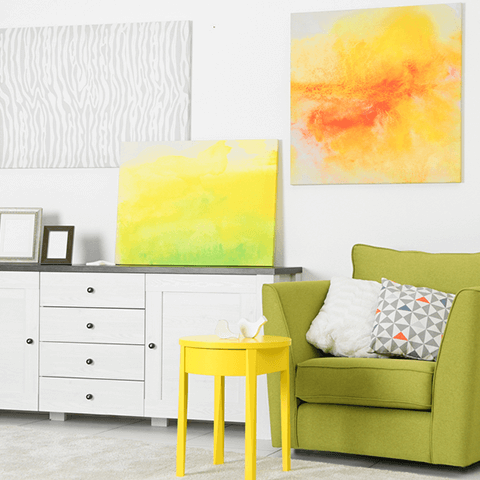 Bright modern living room with lime green sofa, yellow table, white cabinet, and colorful abstract wall art