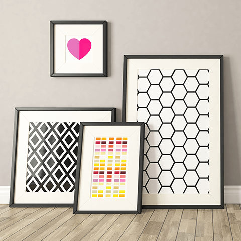 Four framed geometric prints and a pink heart wall art on a light wood floor